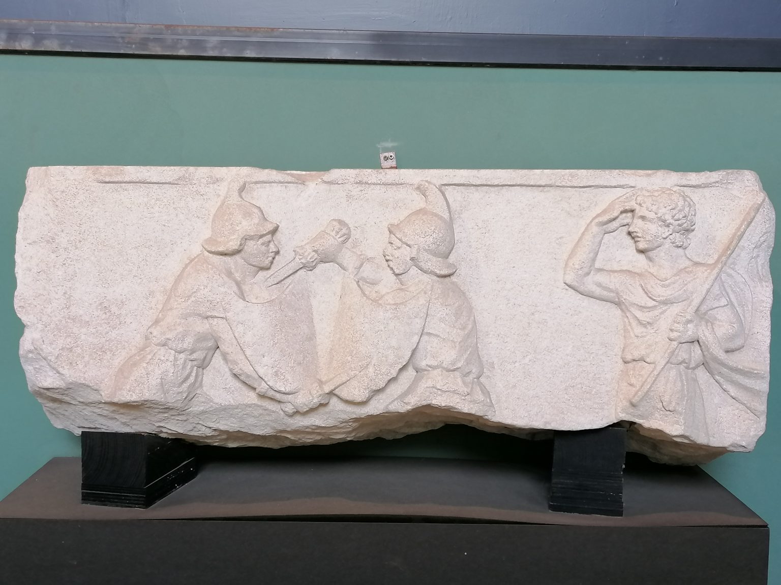 RELIEVE FUNERARIO CON GLADIADORES (finales del siglo I a. C.) Relieve de mármol perteneciente a un sepulcro de Pescorocchiano, antigua Nersae, A la derecha aparece el árbitro (summa rudis) de la disputa con un bastón para separar a los dos combatientes.